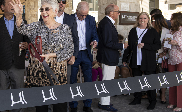 Elaine Davenport, who moved into The Hacienda at Georgetown as its first resident in April 2021, waves as she prepares to cut the ribbon marking the community’s grand opening on Saturday, April 15.