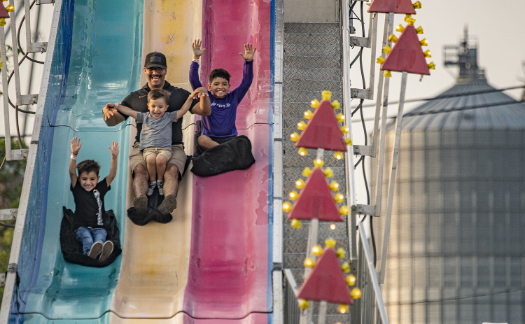 Bryan Perez takes a fast ride on Fun Slide with his children, including (left to right) Damian, 6, Noah, 3 (in dad's lap) and Alorik, 8, on Thursday, May 11, 2023, the opening night of Lakefest in downtown Granger.