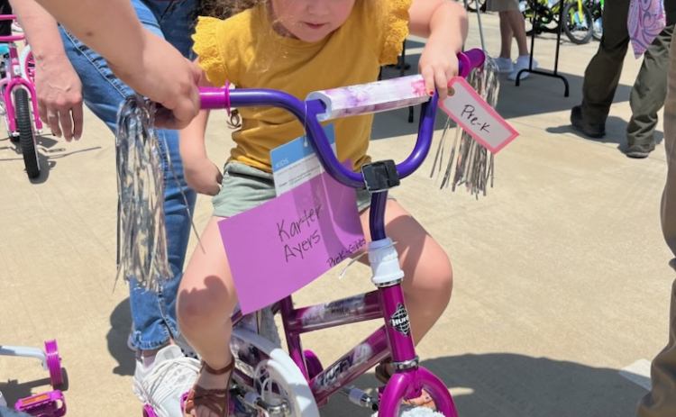 Pre-K student Karter Ayers gets on her new bike in the parking lot of Purl Elementary School on Thursday, May 18. Photo by Abbey Archer