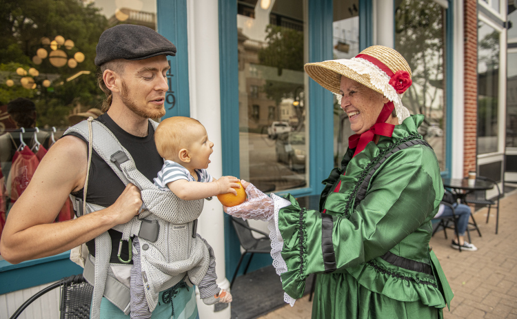 Liz Carbrey Weaver, in her role as Margaret Corinna Henderson Taylor (the wife of Emzy Taylor) is shown  at 7th Street and Austin Avenue on Saturday, May 20, 2023  as she visits with Jeff Stump and his 6-month-old son Azure.