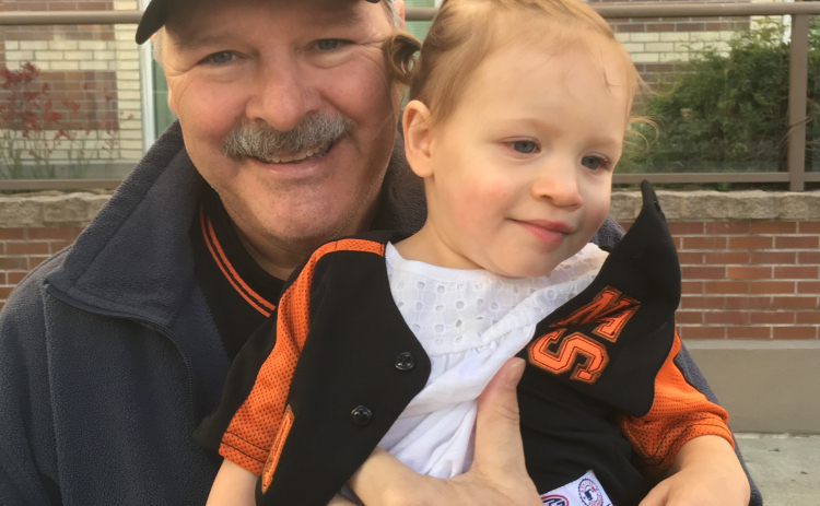 Doug Phariss, who passed in 2022 after battling Alzheimer’s, holds his granddaughter Brynlee.