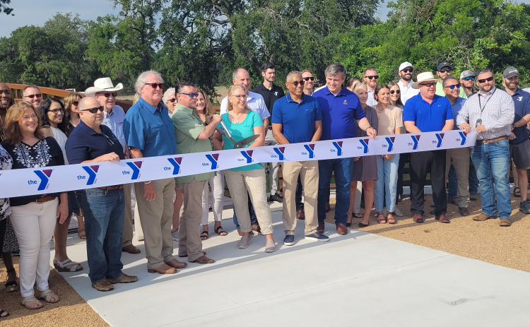 Williamson County Commissioner Cynthia Long, center teal, and The YMCA of Central Texas at Twin Lakes Park cut the ribbon to open a new pedestrian bridge. Photo by Nalani Nuylan