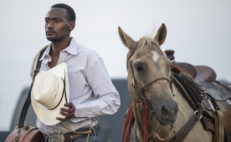 Eddie Dever of Bellville, Texas, competing in Tie Down Roping, stands with his horse Tweetie  during the National Anthem.