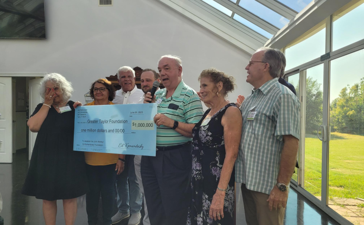 Ed Komandosky, center, presents a $1 million dollar check to Diana Philips, left, wearing black, for the Greater Taylor Foundation’s Impact Taylor initiative.