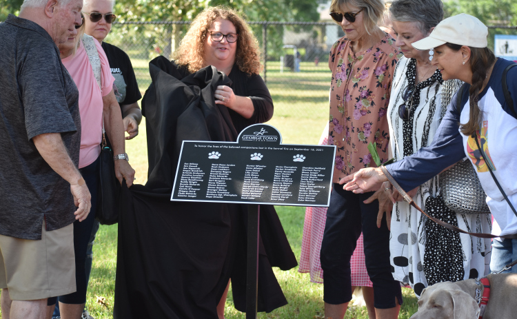 Families of the dogs unveil the plaque honoring pet fire victims at the Georgetown Bark Park.