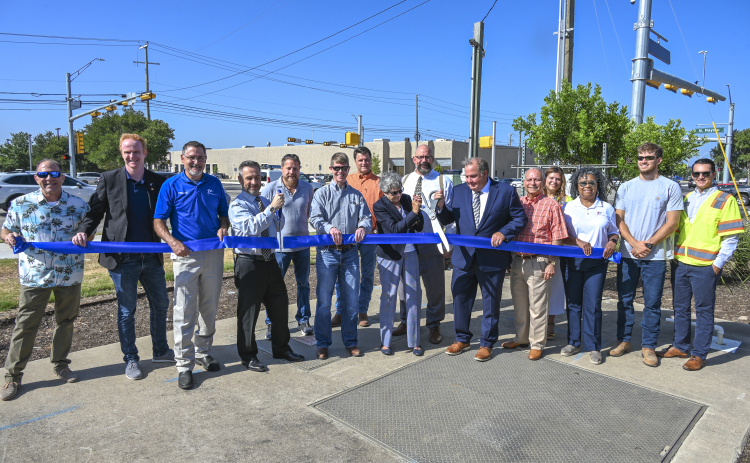 County Commissioners Terry Cook and Russ Boles, along with Round Rock City Council and staff, cut the ribbon celebrating the completion of University Boulevard roadwork July 20. Courtesy the City of Round Rock.