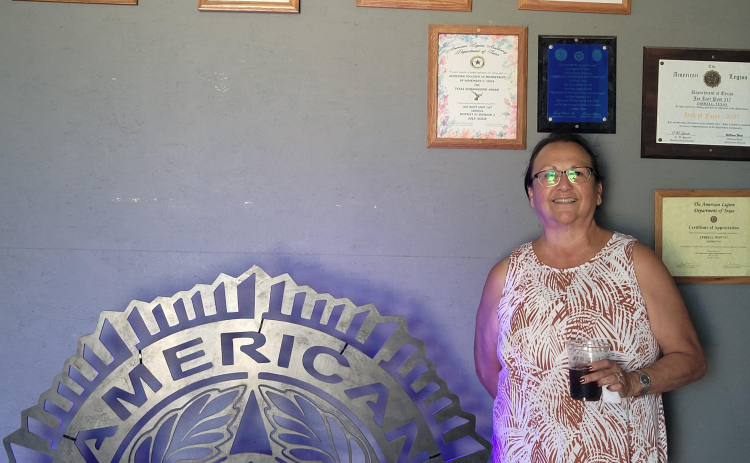 Commander Mary Semek stands next to the Joe Kott American Legion Post 317 sign. It was made by Jarrell High School’s FFA after the Legion donated a scholarship to the program.  Photo by Nalani Nuylan.