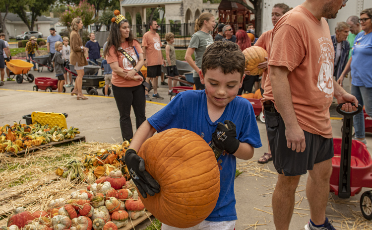 7-year-old Andrew Lake gives maximum effort as he unloads  pumpkins.