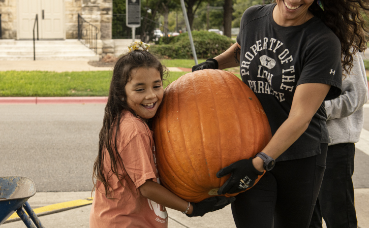 7-year-old Teddi Perez, left, gets help from her mom Jessica Perez as they help  unload  pumpkins at Georgetown's First United Methodist Church on Wednesday, October 11, 2023.