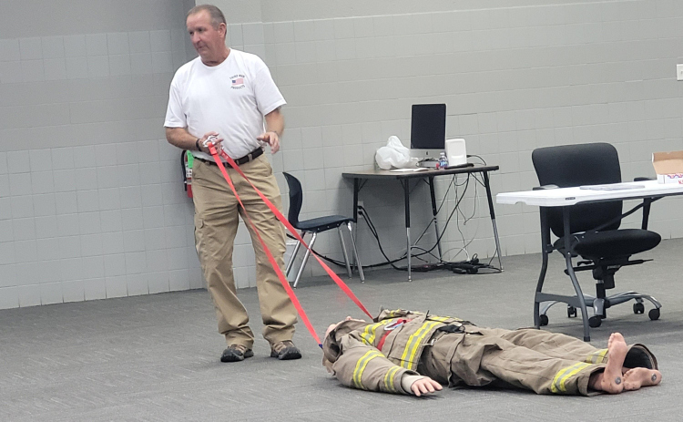 Inventor Charles Ashby explains the improved Hands-Free Extractor at the Jarrell ISD Cafeteria Annex Building on October 11. The invention can be attached at the hips, slung across the shoulder or pulled. Photo by Nalani Nuylan.