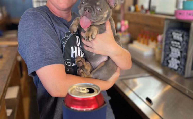 Jodie Hooks, owner of Dog House Drinkery & Dog Park, stands with a happy customer. Photos courtesy Dog House Drinkery & Dog Park