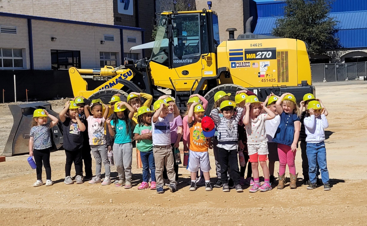 Children from the Chasco Family YMCA Early Childhood Center pose in front of a bulldozer before the groundbreaking ceremony.  Photo by Nalani Nuylan.
