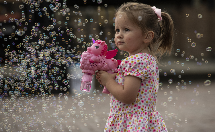  2-year-old Emilia Pustejovsky enjoys making hundreds of bubbles along West Davilla Street on Friday, May 10, 2024, the opening night of the 45th Annual Granger Lakefest.    Photo by Andy Sharp. 