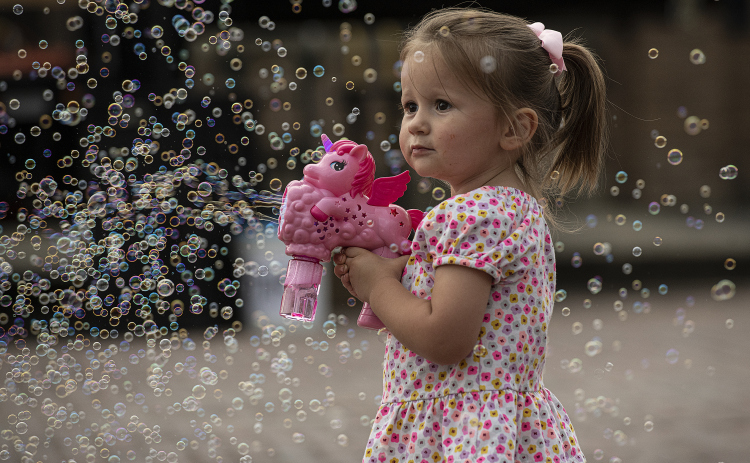 2-year-old Emilia Pustejovsky enjoys making hundreds of bubbles along West Davilla Street on Friday, May 10, 2024, the opening night of the 45th Annual Granger Lakefest.    Photo by Andy Sharp.