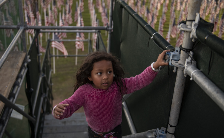 Milove Helgerson, 4, climbs the stairs to the viewing area for American flags that adorn a field behind the Hammerlun Center for Leadership and Learning on November 3, 2023.