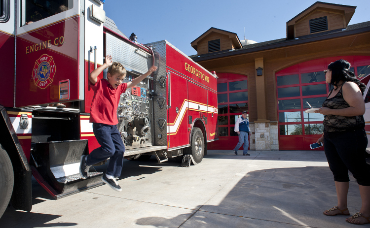 7-year-old Max Acker makes a big leap from a fire engine he looked over at the dedication ceremony of the Georgetown Fire Department's new Station 2 on Saturday, March 16, 2013.