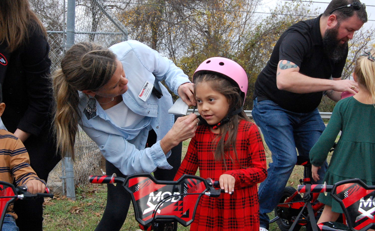 Emily Baker, left, helps Ariyah Robles adjust the strap on her helmet.