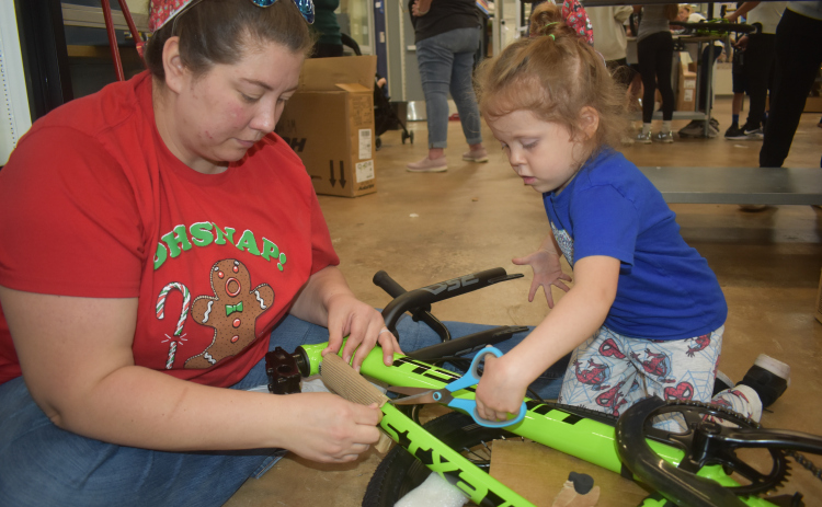 Little Remmington Heppner and her mom, Emma, get started on a bike assembly. “We’re helping people that doesn’t have bikes,” Remmington said.