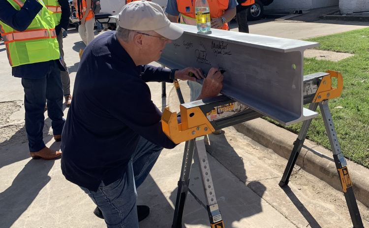 Community member Larry Olson, who provided resident input on the parking garage, signs a beam that will go inside the garage. Other members of city staff and developer Swinerton also signed. (Photos by Kaitlyn Wilkes)