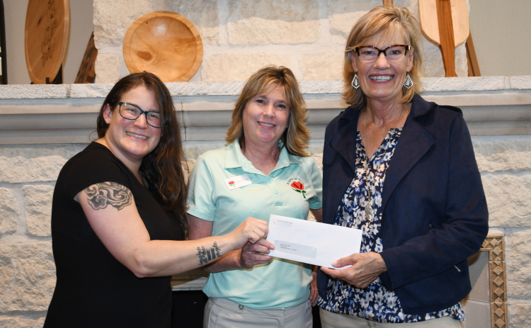 From left, A Gift of Time’s Community Educator Carolina Umana and Executive Director Becky Folta-May receive a WHO donation from WHO VP Judy Madsen.
