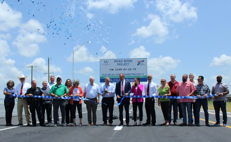 In center U.S. Rep. Pete Sessions, 17th District; Russ Boles, Williamson County commissioner, Precinct 4; Steve Snell, Williamson County judge; Caroline Harris Davila, state representative and Marc Williams, executive director of TxDOT cut the ribbon to open the East Wilco Highway, June 20. Photo by Nalani Nuylan.