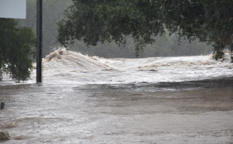 The San Gabriel River roars through Blue Hole Park. Water covers Rock Street up to Second Street in Georgetown.