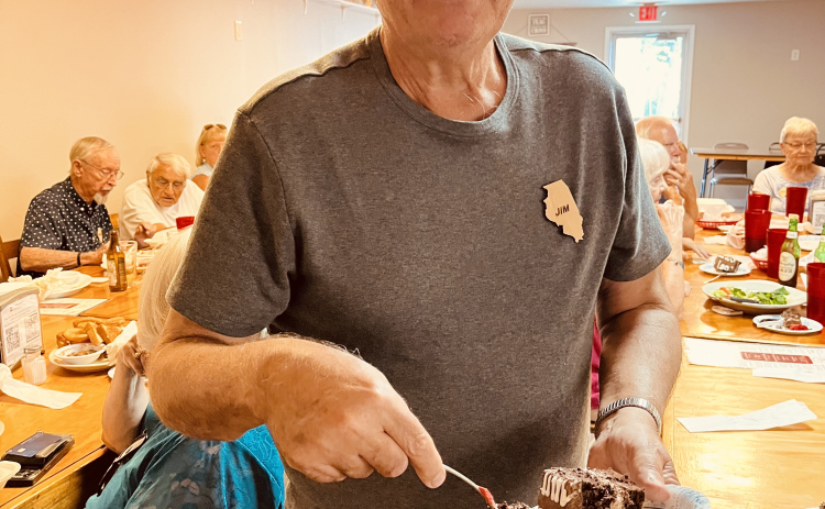 Chicago Club president Jim Bonk grabs a slice of chocolate cake to celebrate Pope Leo XIV. Photo by Linda Dwyer