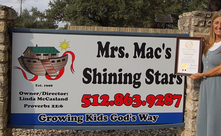 Linda McCasland stands with her Yellow Rose of Texas award in front of the sign for Mrs. Mac’s Shining Stars Preschool, the business she owns. (Photo by Kaitlyn Wilkes)