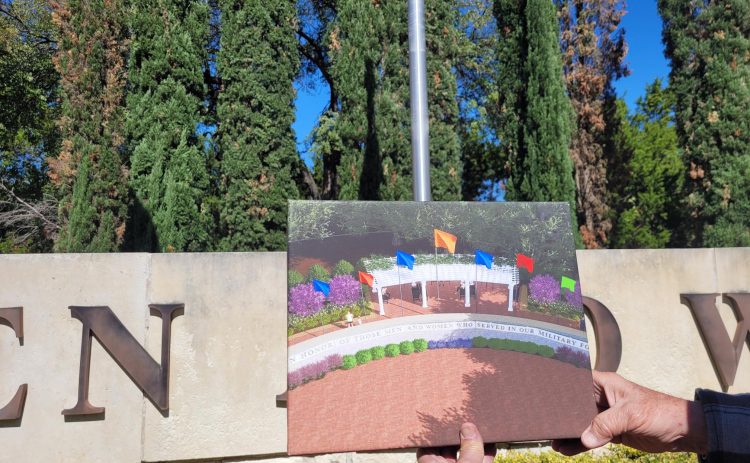 A rendering of what the Veterans Memorial will look like is held up by Tom McCabe against its current state in the background. Photo by Nalani Nuylan.
