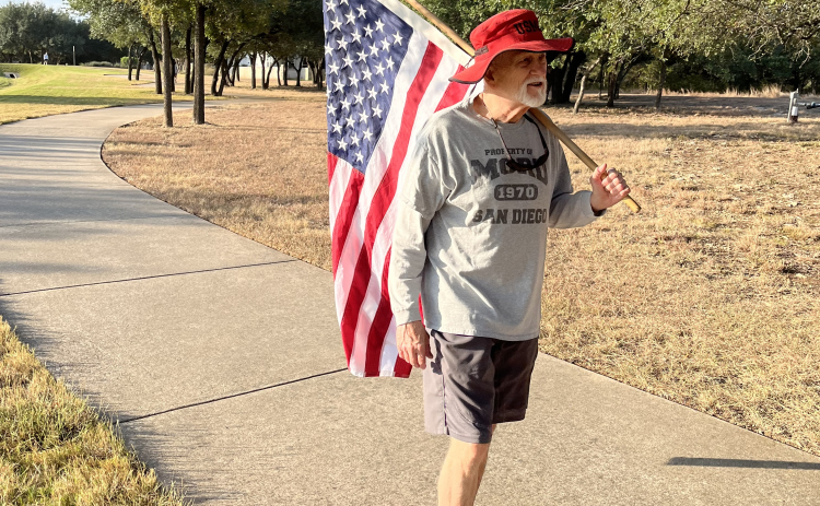 Mike Stankovich walks with an American flag near Sun City Boulevard.