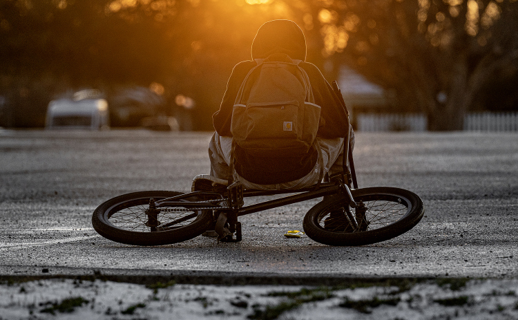 A bicyclist takes a rest break in a parking lot at Murphy Park  as sunset nears on an icy Monday afternoon, January 26, 2026.  The temperature reached the low-mid 30s Monday, and dipped into the teens overnight.  Photo by Andy Sharp.