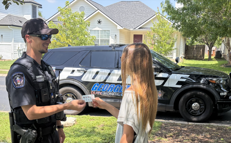 Officer Eric Campbell, left, hands out a coupon for safe behavior. (Photo courtesy Georgetown Police Department)