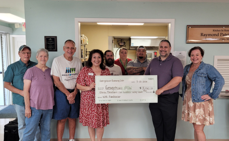 Raymond Husser, from the Georgetown Running Club (center right) presents a $11,562.37 check to Opportunities for Williamson and Burnet Counties’ Meals on Wheels program at the Georgetown Meals on Wheels location, 803 West Eighth Street, on July 10. Meals on Wheels staff and volunteers accompany Mr. Husser. Photo by Nalani Nuylan.