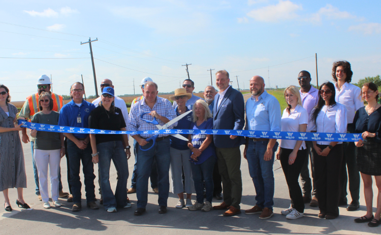 Commissioner Russ Boles, center, holds ceremonial scissors during the County Road 460 ribbon cutting on Thursday, July 30. The project helps with access to the new Coupland ISD junior high and high school.   Photo courtesy of Williamson County