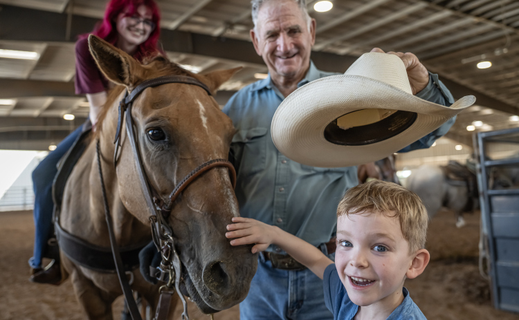 Ed Denison of Hockley, Texas, who will be 80 in October introduces his horse called Hombre to his grandson, 8-year-old Levi Bentley and family friend McKenna Degarmo, 17, (sitting on Hombre) during the Texas Senior Pro Rodeo Association’s Rodeo held Sunday, August 16, 2026  at the Williamson County Expo Center. Denison has been competing in rodeos for decades.  Texas Senior Rodeo Association competitors must be at least 40-years-old to compete.  Many are in their 70s and 80s. Photo by Andy Sharp