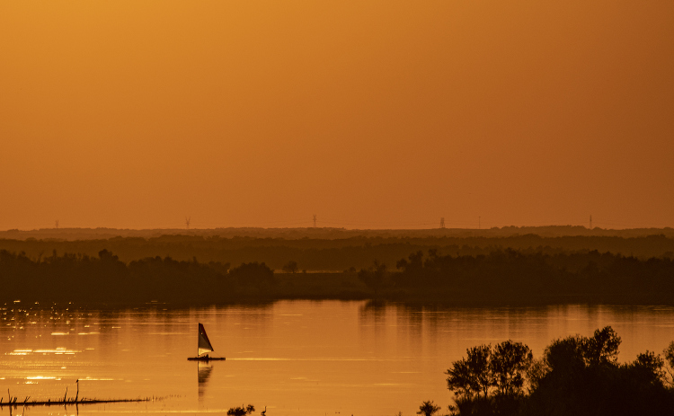A sailboat glides through Granger Lake water  near the Granger Lake Dam near sunset  on Tuesday, October 15, 2024.