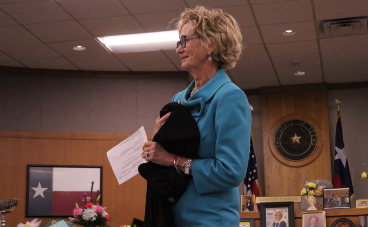Judge Betsy Figer Lambeth of the 425th District Court clutches a Judges robe as she gives a speech at her retirement ceremony in the 277th District Courtroom on August 21. Her mother made the robe for Judge Lambeth’s swearing in ceremony on January 1, 2013. Photo by Nalani Nuylan.