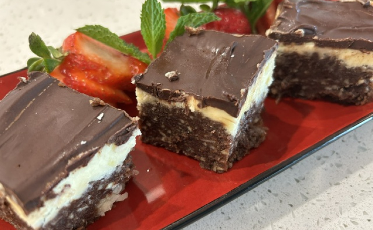 essamy’s Nanaimo Bars are plated with mint and strawberries on the side.