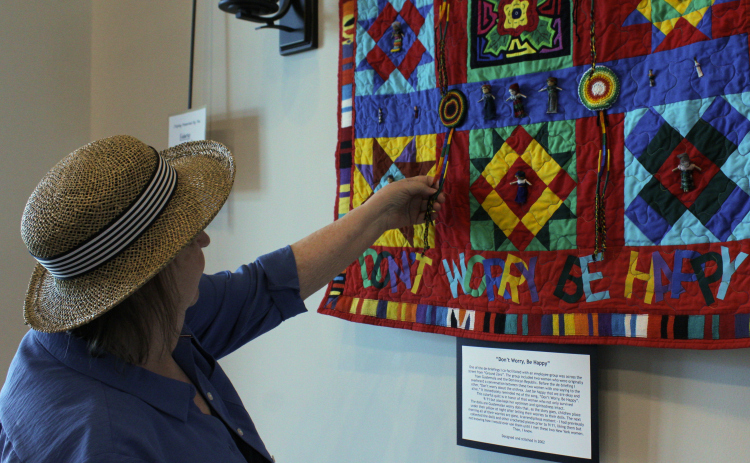 Sun City artist Susan Hoppenworth explains the significance of the Guatemalan belts and bookmarks in her quilt “Don’t Worry, Be Happy.” The quilt is one of nine on display in a 9/11 memorial gallery in Sun City. Photo by Nalani Nuylan.