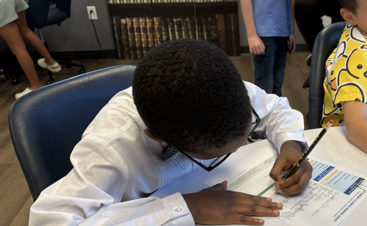 JJ Ahanobi-Ikekwere, age 7, works on a mock-trial case workshop. He is figuring out whether or not the big bad wolf blew down the pigs house. Photo by Abbey Archer