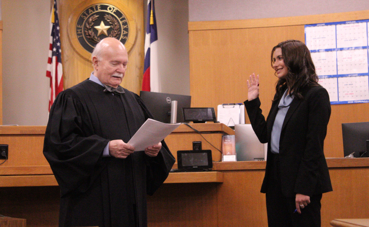 Camryn Whitman takes the oath to become an Assistant District Attorney for Williamson County on Friday, October 16, in the 368th District courtroom, where her grandfather, the late Judge Burt Carnes, presided. Judge Billy Ray Stubblefield administered the oath. Photo by Nalani Nuylan.