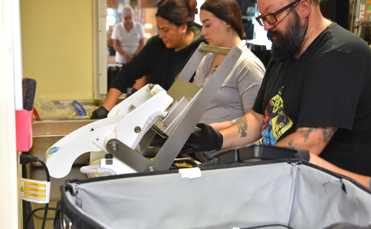 Volunteers at the Madella Hilliard Senior Center, 803 West Eighth Street, pack meals and vacuum seal them for lunchtime delivery for Meals on Wheels. (Photo by Kaitlyn Wilkes)