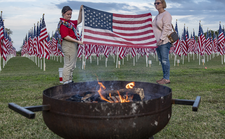 Left, American Heritage Girls troop member Maria Combs, 15, left, and Army veteran Wanda Clark, right, prepare a flag for retirement the evening of Wednesday, November 9.