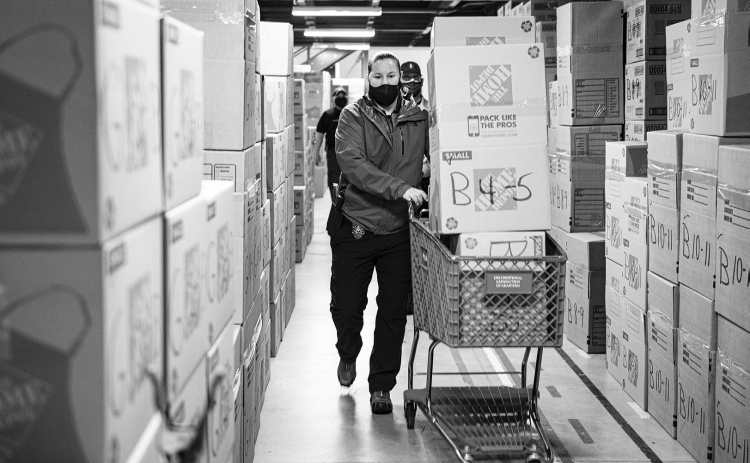 Cook-Walden Davis Funeral Home is hosting its Blue Santa gift drive this Saturday, December 3, one of many drives hosted throughout the community during the holidays. In this photo, Georgetown Police Department officer Kandice Ellis uses a shopping cart to deliver Christmas gift boxes during the 2020 Blue Santa. SUN ARCHIVE
